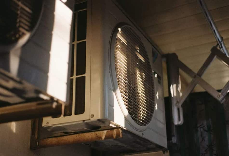 Homeowner checking an outdoor AC unit and clearing debris before calling for cooling repair in Meridian, Idaho